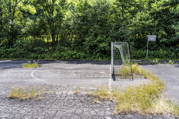 Old sports field, with asphalt floor, weeds reclaiming the field, apparently abandoned football