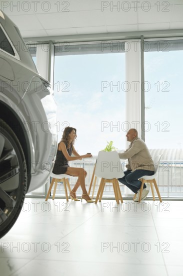 A customer and a salesperson are engaged in a discussion at a small table inside a sleek car