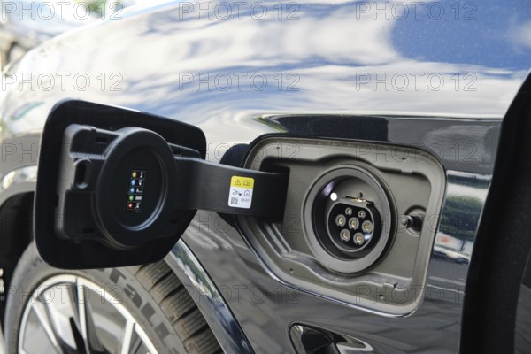 Close-up view of electric vehicle charging port during bright daytime at urban charging station.