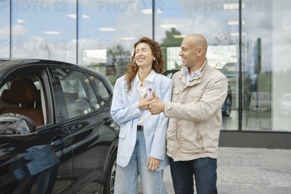 A couple is happily engaged in a conversation while selecting a new car at a dealership. The woman