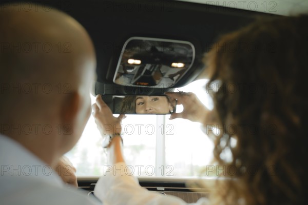The view from the rear seat of the car is a couple of sitting in front. A woman sets up a rear view