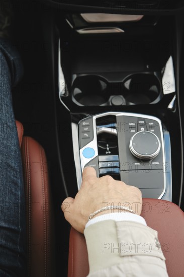 A driver is adjusting the controls in a luxury vehicle. The focus is on the comfortable leather