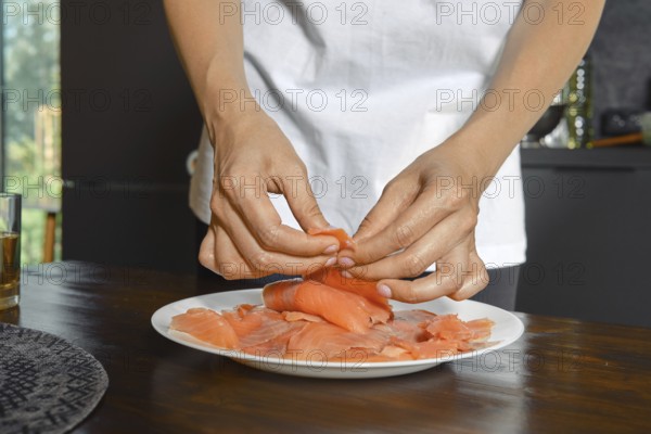 Hands expertly handle smoked salmon fillets on a plate, showcasing a focus on healthy food