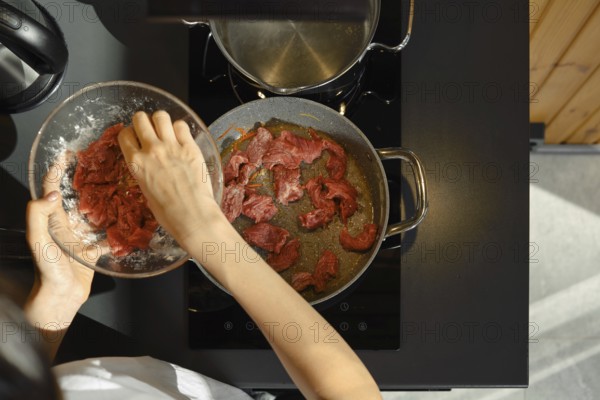 Slicing lean beef into strips and adding it to a hot pan, this skilled cook is preparing a healthy