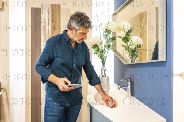 Architect using tablet while checking bathroom sink in home improvement store, evaluating materials