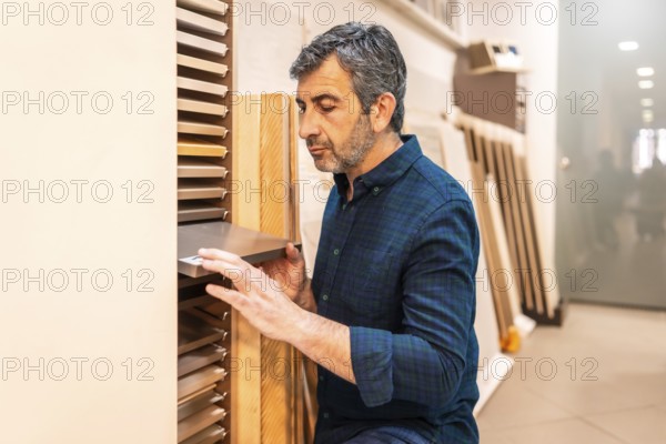 Carpenter selecting samples of wooden and metallic materials in a home improvement store for his