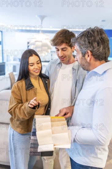 Couple choosing upholstery fabric from a wide variety of swatches held by a home improvement store