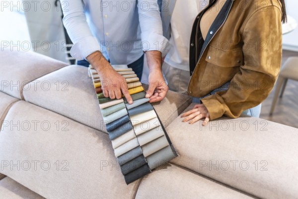 Salesman showing fabric swatches to a customer choosing upholstery for a new sofa in a furniture