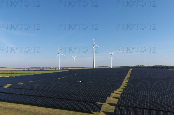 Solar panels and wind turbines on a wide field under a clear sky, near Kitzingen, Lower Franconia,