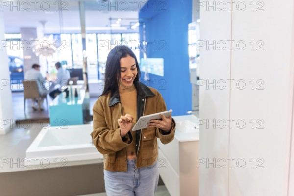 Smiling female customer using digital tablet, choosing bathroom fixtures in home improvement store