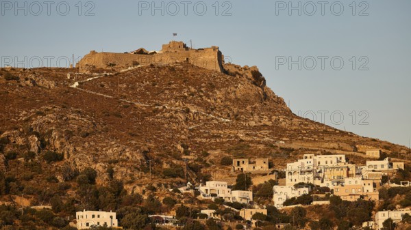 Settlement with castle on a hill in the warm light of the evening sun, surrounded by vegetation,