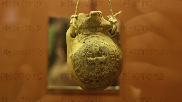 Ancient clay seal in a museum, hung with rope and detailed engravings, Archaeological Museum, Agia