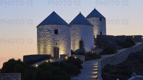 Illuminated windmills in the twilight on a stony hill, Pandeli Castle, castle, Leros fortress, St