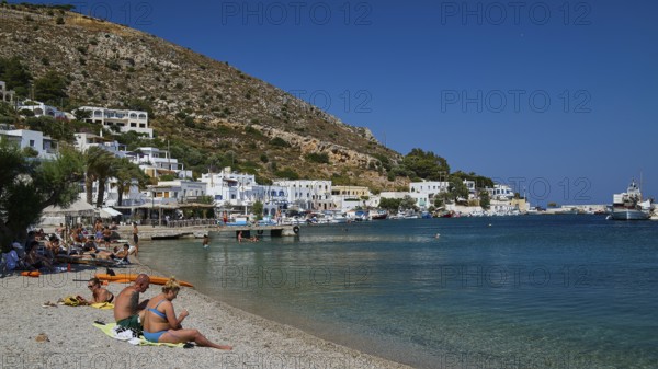 People relaxing on a sunny beach in a Greek coastal settlement, Pandeli Beach, Pandeli Castle,