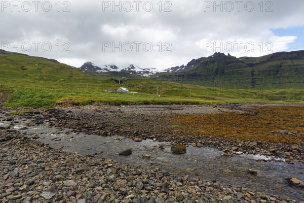 Rocky volcanic landscape near Grundarfjördur, snow-capped mountains on the horizon, Snæfellsnes