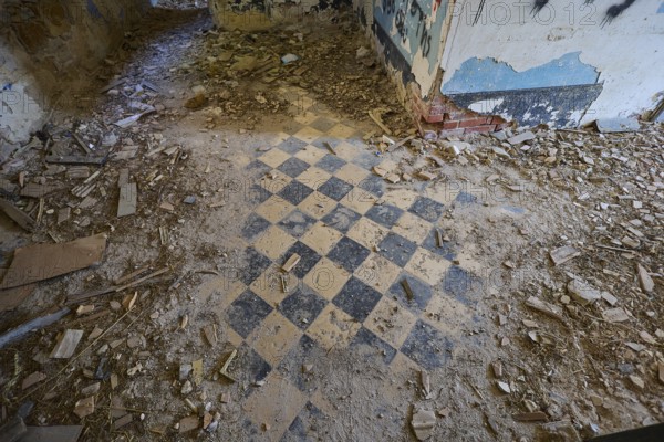 Lost Place, chequered pattern on the floor of a dilapidated room, surrounded by rubble and blue