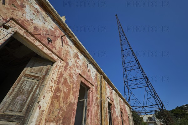 Lost Place, Old building with metal structure in the background, antenna mast, peeling plaster and