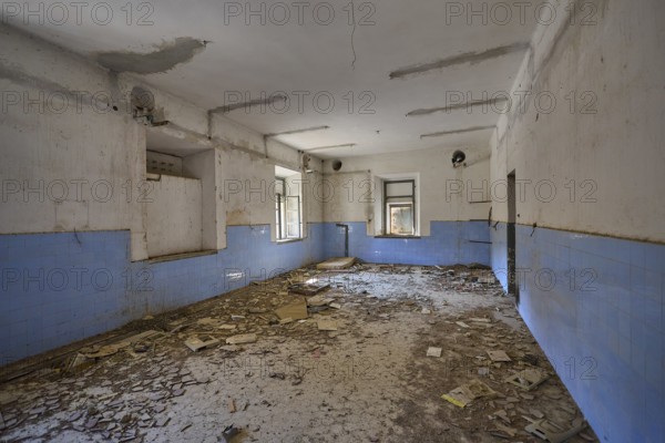 Lost Place, Abandoned room covered with rubble, blue wall plaster and damaged ceiling visible,