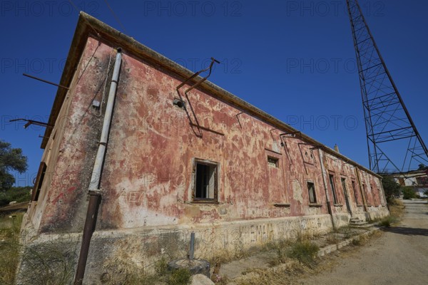 Lost Place, Red, peeling building with electric poles and cables under the open sky, Antenna mast,
