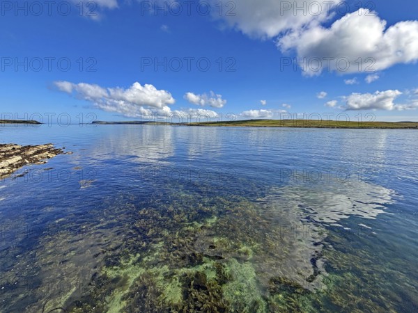 Clear sea with calm atmosphere, blue sky and clouds along the coastline, Hoy, Orkney Islands,