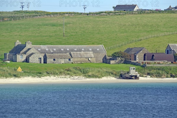 Rural scene with houses by the sea and green fields in the background, Lambholm, Orkney Islands,
