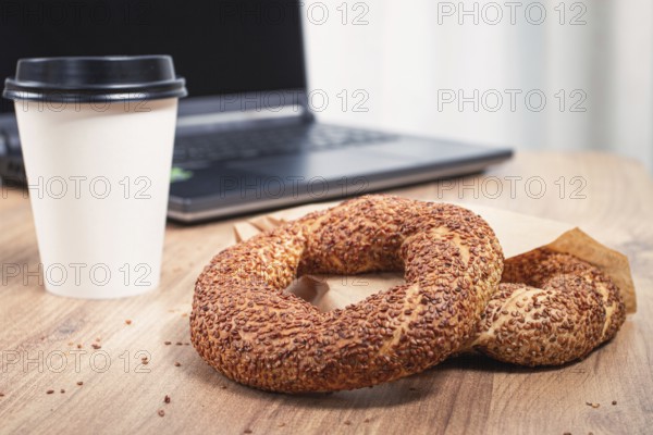 Simits with coffee on a wooden table, with a laptop, in a cozy working environment, snack,
