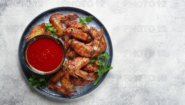 Fried in the oven, chicken wings, with spices, tomato sauce, on a plate, gray background, no