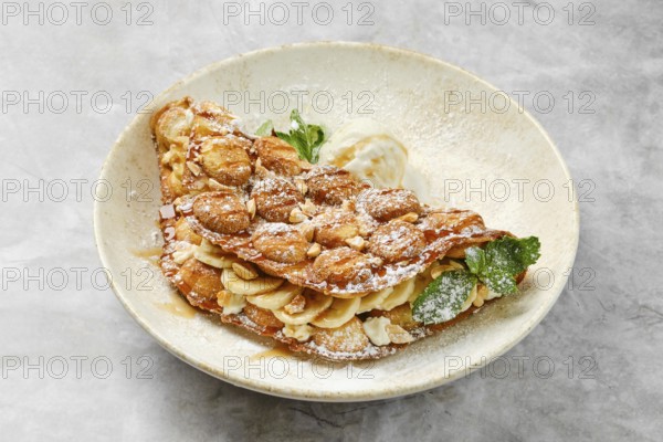 A beautifully presented dessert showcases a crispy waffle filled with sliced bananas and caramel,