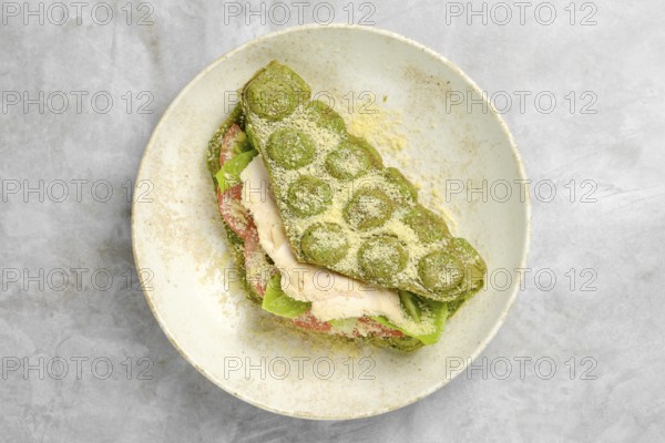 A vibrant green wrap is layered with fresh lettuce, slices of tomato, and tender chicken, resting