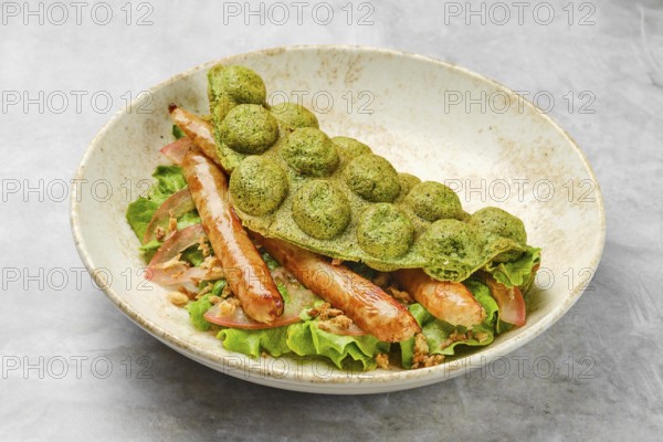 A vibrant green waffle is placed atop a bed of fresh lettuce, featuring tender grilled sausage and