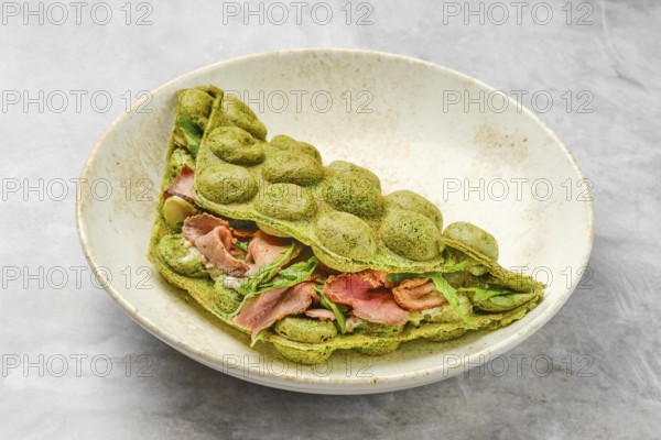 A matcha pancake showcases a vibrant green hue, folded elegantly with layers of savory ingredients