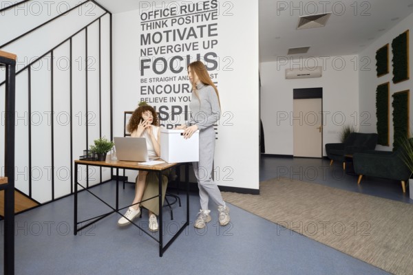 Woman speaks on the phone sitting in coworking and looks at her colleague in surprise, who brought