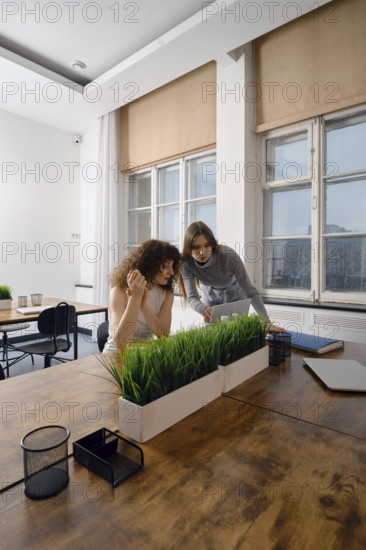 In a modern workspace, two women engage in a focused discussion about women's health initiatives.