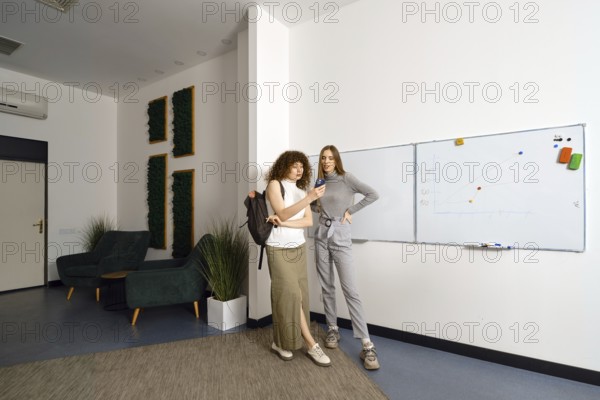 At the end of a productive working day in coworking, two women called a taxi online and look at the