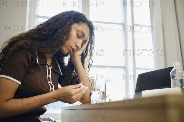 A woman experiences pain during menstruation and is forced to take painkillers while working