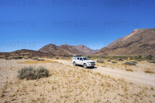 Off-road vehicle on a sandy track, desert landscape with Brandberg, Erongo, Damaraland, Namibia