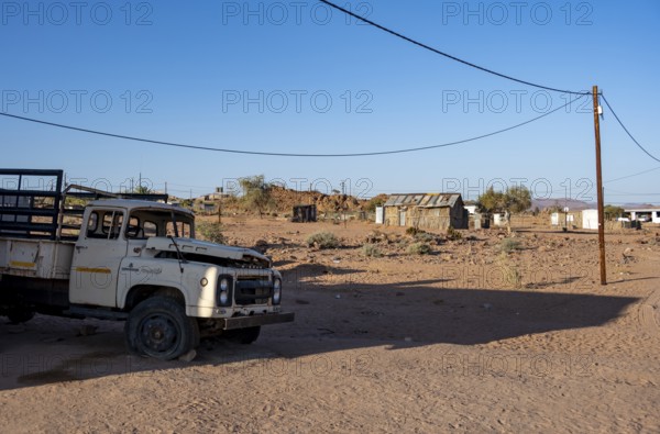 Old transport vehicle and simple houses made of wood and mud in a small village, Erongo,