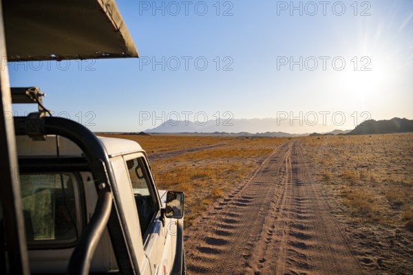 View from a safari vehicle, sandy track in desert landscape, in the evening light, Brandberg,