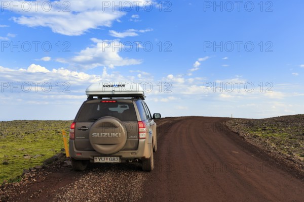 SUV Suzuki Grand Vitara with roof tent, travelling on a gravel road, Cumulus, Latrabjarg headland,