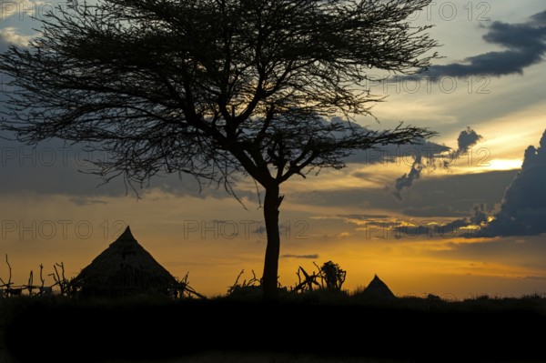 Silhouette of conical huts of the Hamer ethnic group against a dramatic sunset sky, Southern Omo