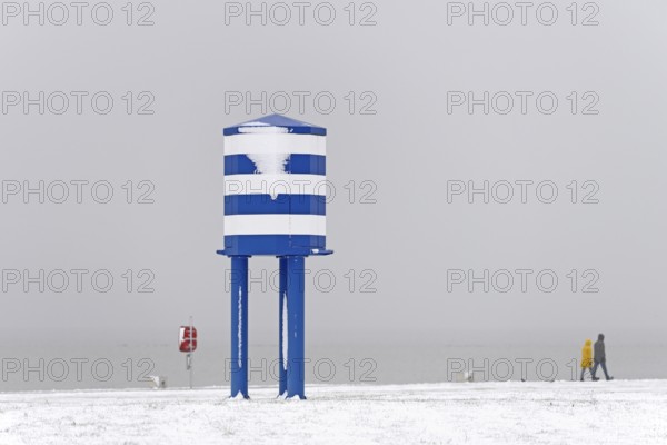 Winter day, onset of winter, snow on the North Sea coast, people walking on the beach promenade of