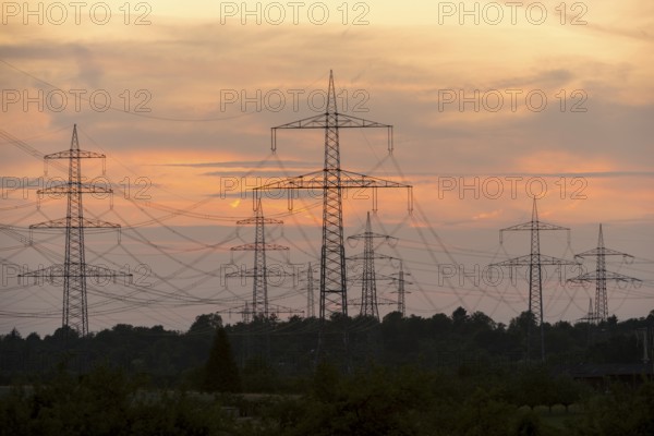 Electricity pylons in front of a pastel-coloured sunset sky with clouds, Waiblingen,