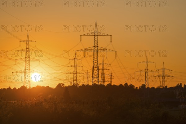 Imposing silhouettes of electricity pylons in front of an intense sunset, Waiblingen,