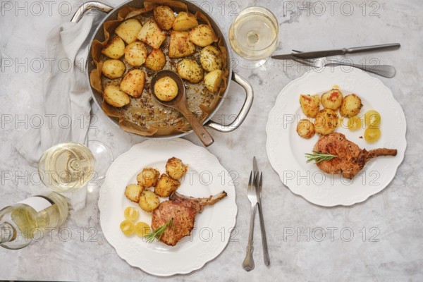 Pork rib roast paired with crispy golden potatoes on white plates. Enjoy this inviting meal set on