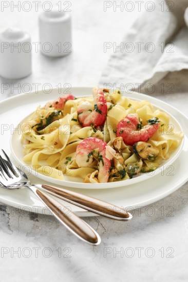 A delectable portion of fettuccine allo scoglio sits elegantly on a white plate. The dish features