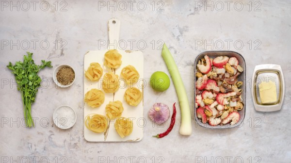 Fresh ingredients for fettuccine allo scoglio, including seafood, pasta, herbs, and vegetables.