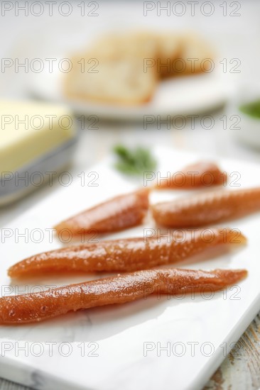Herring caviar glisten with a rich color, artfully arranged on a marble platter. In the background,
