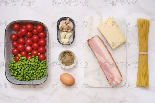 Overhead view of fresh cherry tomatoes, green peas, smoked bacon, garlic, parmesan cheese,