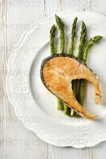 Grilled salmon on a round white dish alongside roasted asparagus spears. The vibrant green