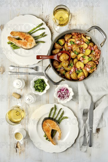 A beautifully arranged dining table features two plates of grilled salmon served with roasted